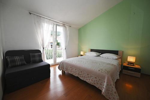 a bedroom with a bed and a chair and a window at Apartments MajaPaula in Slatine