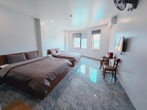 a bedroom with two beds and a table and chairs at Khách Sạn Như Ý in Làng Lap