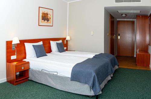 a bedroom with a large bed with a blue blanket at Hotel Rigga in Władysławowo