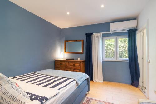 a blue bedroom with a bed and a window at Casa felix in Loulé