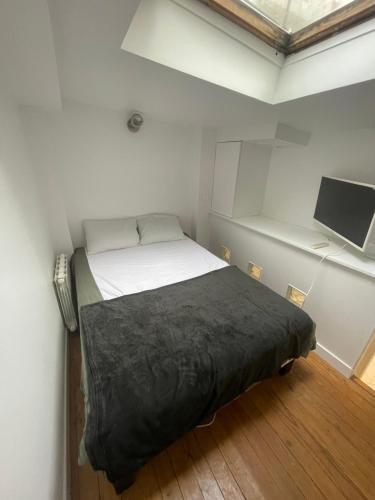 une petite chambre avec un lit et une télévision à écran plat dans l'établissement Appartement à côté du Sacrée cœur et Montmartre, à Paris