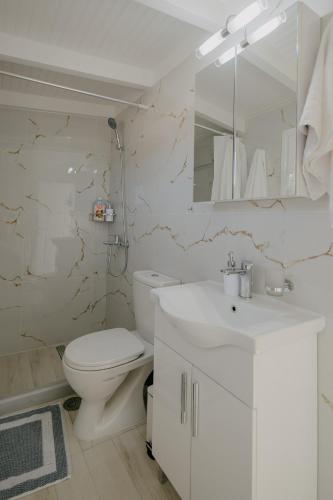 a white bathroom with a toilet and a sink at Catherine's View in Agios Rokkos