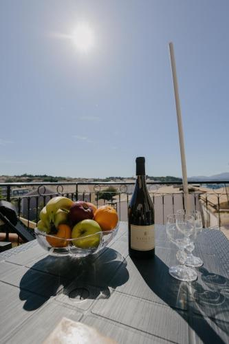 a bowl of fruit on a table with a bottle of wine at Catherine's View in Agios Rokkos