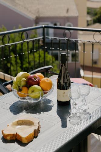 a table with a bowl of fruit and a bottle of wine at Catherine's View in Agios Rokkos
