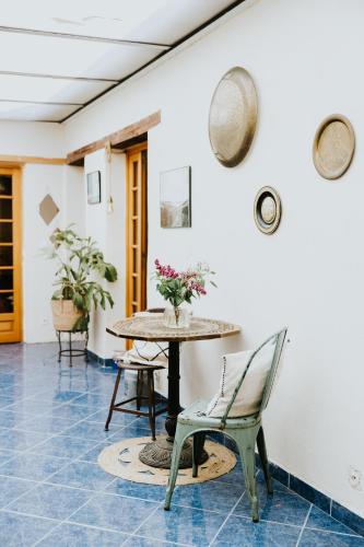 Cette chambre est dotée d'une table, de chaises et de fleurs. dans l'établissement Maison La Pomaré, à Villeneuve-les-Genêts