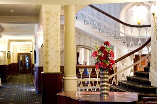 a vase with red flowers on a table in a building at Duke Of Cornwall Hotel in Plymouth