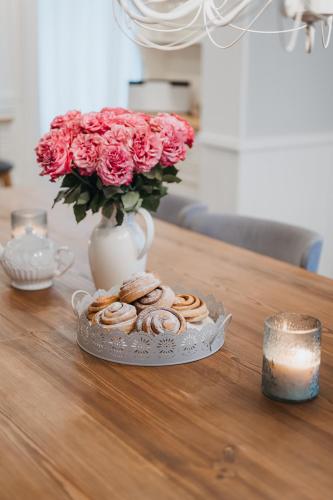 a table with a plate of pastries and a vase with roses at Wiigi Family Home & Spa in Haapsalu
