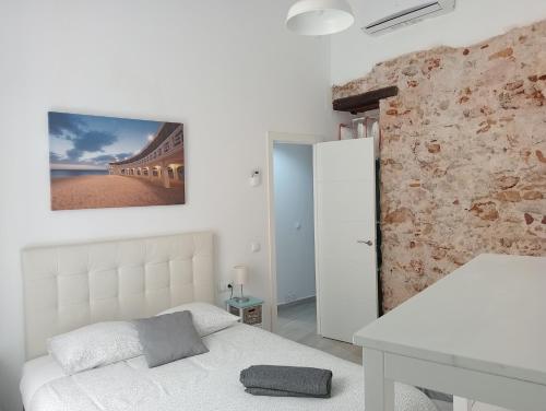 1 dormitorio con cama blanca y pared de piedra en La Caleta de Cadiz WiFi, en Cádiz