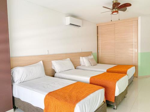 two beds in a hotel room with a fan at Hotel Cabreromar By GEH Suites in Cartagena de Indias