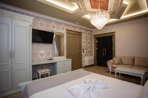 a bedroom with a bed and a couch and a chandelier at Ervini Boutique Hotel in Shkodër