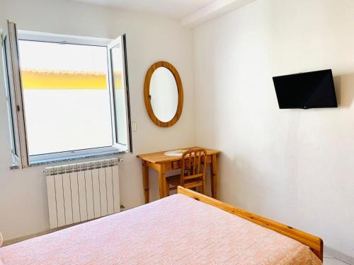 a bedroom with a bed and a mirror and a window at Pensione Casa Verde in Ischia