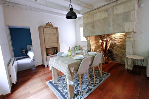 ein Esszimmer mit Tisch und Kamin in der Unterkunft Appartement le Clarté in Périgueux