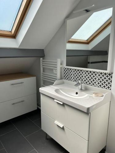 une salle de bain blanche avec un lavabo et un miroir dans l'établissement Villa des Arts, à Argenteuil