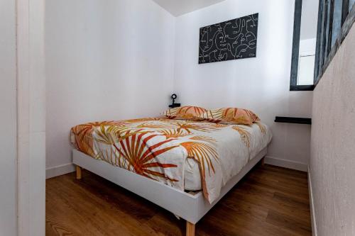 ein Schlafzimmer mit einem Bett mit einer Bettdecke darauf in der Unterkunft Les conviviales Quartier théâtre gare in Sète