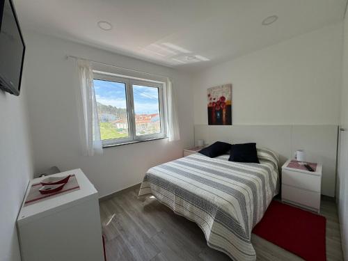 LOFT AS CASETAS PEREGRINOS في Rosal: غرفة نوم بيضاء بها سرير ونافذة