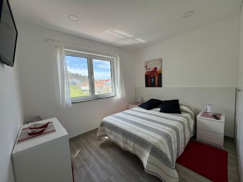 a white bedroom with a bed and a window at LOFT AS CASETAS PEREGRINOS in Rosal