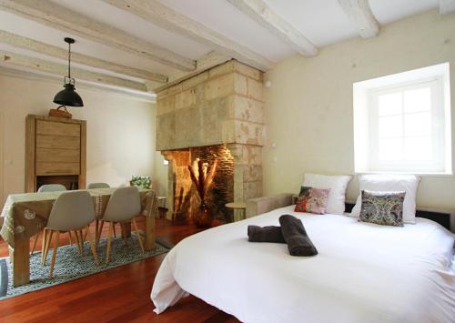ein Schlafzimmer mit einem großen weißen Bett und einem Kamin in der Unterkunft Appartement le Clarté in Périgueux