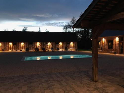 une piscine éclairée devant un immeuble dans l'établissement Le grand Epilly, à Chaumont-sur-Tharonne