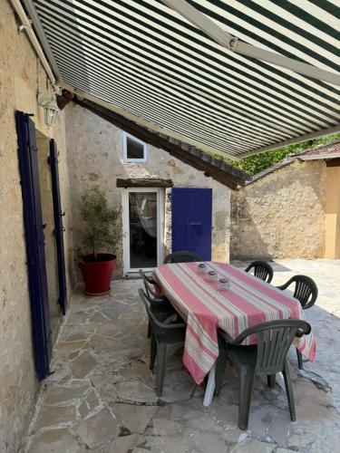 d'une terrasse avec une table et des chaises ainsi qu'une porte bleue. dans l'établissement La Maison Bleue Classée 3 étoiles, à Limeyrat