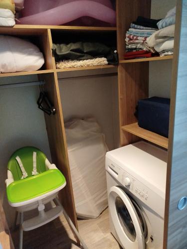 un placard avec une machine à laver et un tabouret vert dans l'établissement Chez thomas et Stéphane, à Gastes