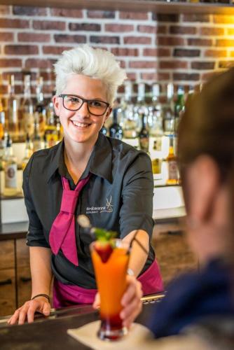 a woman sitting at a bar with a drink at Stratmanns Hotel in Lohne