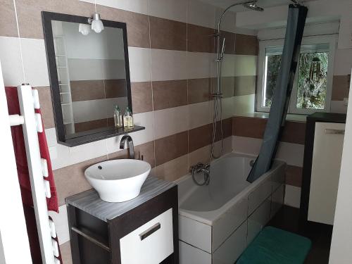 a bathroom with a sink and a tub and a mirror at Appart cosy aux écluses du port in Morlaix