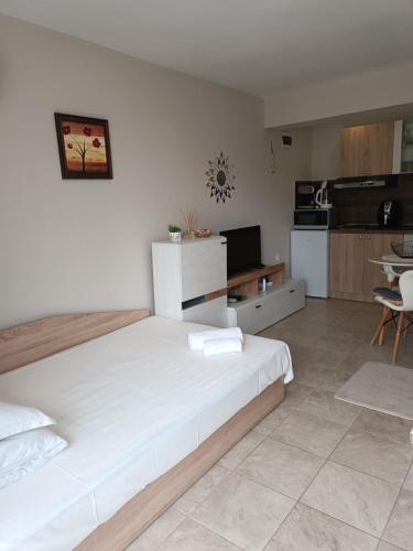 a bedroom with a large white bed and a kitchen at Megi Apartments, Nesebar sity in Nesebar