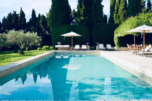 une piscine avec chaises et parasols dans une cour dans l'établissement LA PONCHE, à Vacqueyras