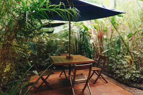 a table and chairs with an umbrella in a garden at Sazagua Hotel Boutique in Pereira