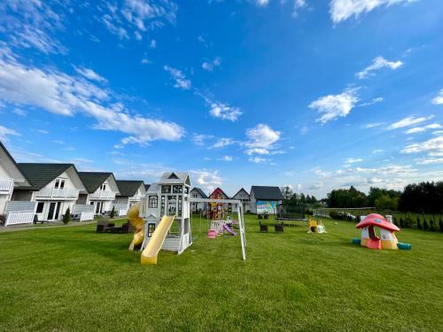 a playground with slides and play equipment on a lawn at Słonecznikowa Dolina in Sarbinowo