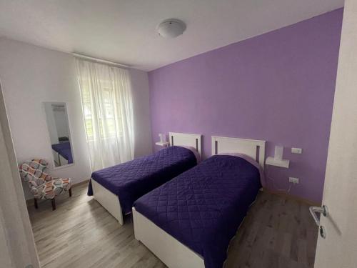 two beds in a purple room with purple walls at Villa Vittoria in Stresa