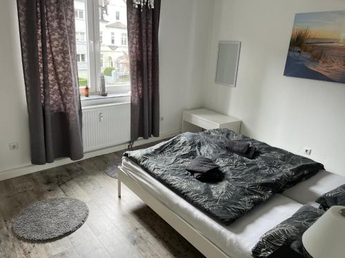 a bedroom with a bed with a black comforter and a window at Geräumige, moderne 110 qm Wohnung Nähe Messe Essen in Essen