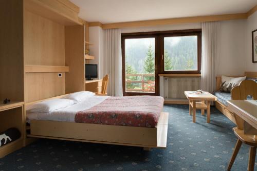 um quarto de hotel com uma cama e uma grande janela em Apartments Boè em Santa Cristina in Val Gardena