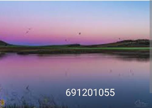 a painting of a lake with a pink and purple sky at San Antonio cuatro vientos in Pétrola