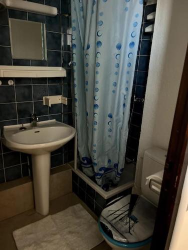 La salle de bains est pourvue d'un lavabo et d'un rideau de douche bleu. dans l'établissement St-Pierre-La-Mer, bel appartement a dans residence avec piscine et tennis entre 5 et 10 min de la plage, à Fleury