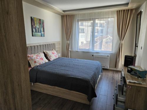 a bedroom with a bed and a large window at AMORA Apartment in Dobrich