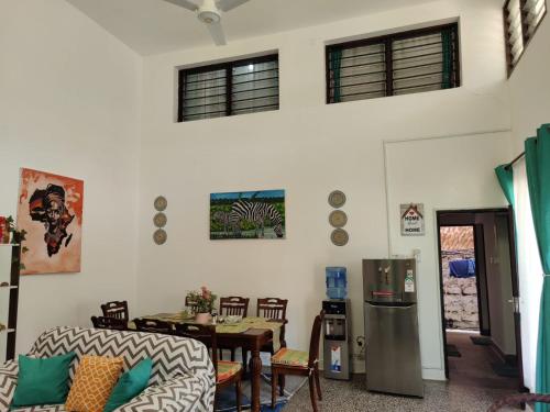 a living room with a table and a refrigerator at Monica's Cottage Diani Beach Kenya in Diani Beach