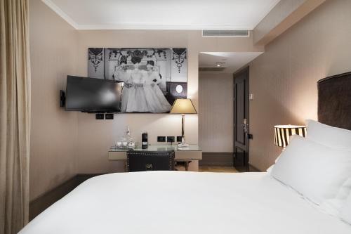 a hotel room with a bed and a dress on the wall at Hotel B Berdichevsky in Tel Aviv