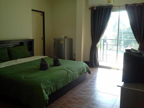 um quarto com uma cama verde com dois gatos em Bansappoori em Lamphun