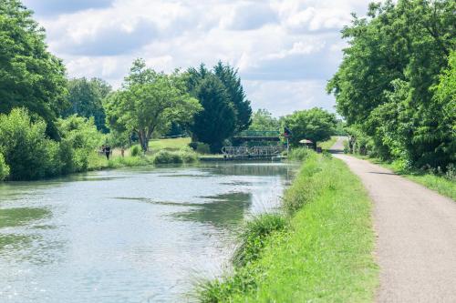 un chemin à côté d'une rivière avec un pont dans l'établissement Gîte Lilou le clos st jean, à Saint-Jean-de-Thurac