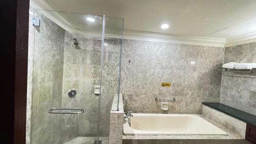 a bathroom with a tub and a glass shower at 100 Service suites At Times Square KL in Kuala Lumpur