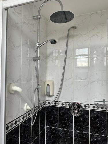 a shower with a shower head in a bathroom at Malahide Guest Rooms in Malahide