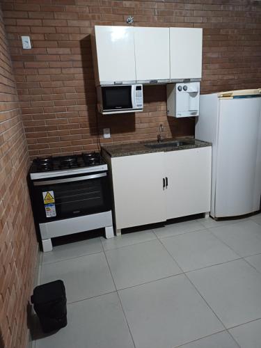 a kitchen with white appliances and a brick wall at Casa aconchegante in Bragança Paulista