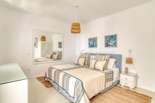 a white bedroom with a bed and a mirror at Villa Bellonia in Naousa