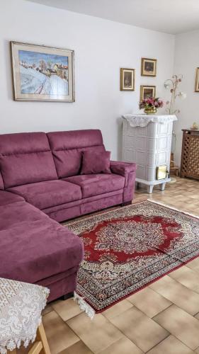 a living room with a purple couch and a rug at Appartamento "Vista Lago" in Auronzo di Cadore