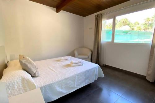 ein Schlafzimmer mit einem weißen Bett und einem Fenster in der Unterkunft Finca House by Fataga Maspalomas in San Bartolomé de Tirajana