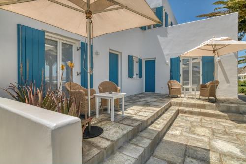 eine Terrasse mit einem Tisch, Stühlen und einem Sonnenschirm in der Unterkunft Villa Bellonia in Naoussa