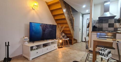 un salon avec une grande télévision et un escalier dans l'établissement La Petite Maison de l'Oze, à Verrey-sous-Salmaise