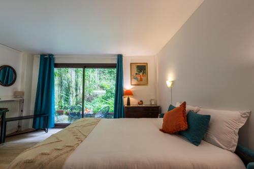 - une chambre avec un grand lit doté de rideaux bleus et d'une fenêtre dans l'établissement Studio à montmartre avec terrasse, à Paris