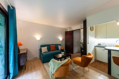 un salon avec un canapé bleu et une cuisine dans l'établissement Studio à montmartre avec terrasse, à Paris